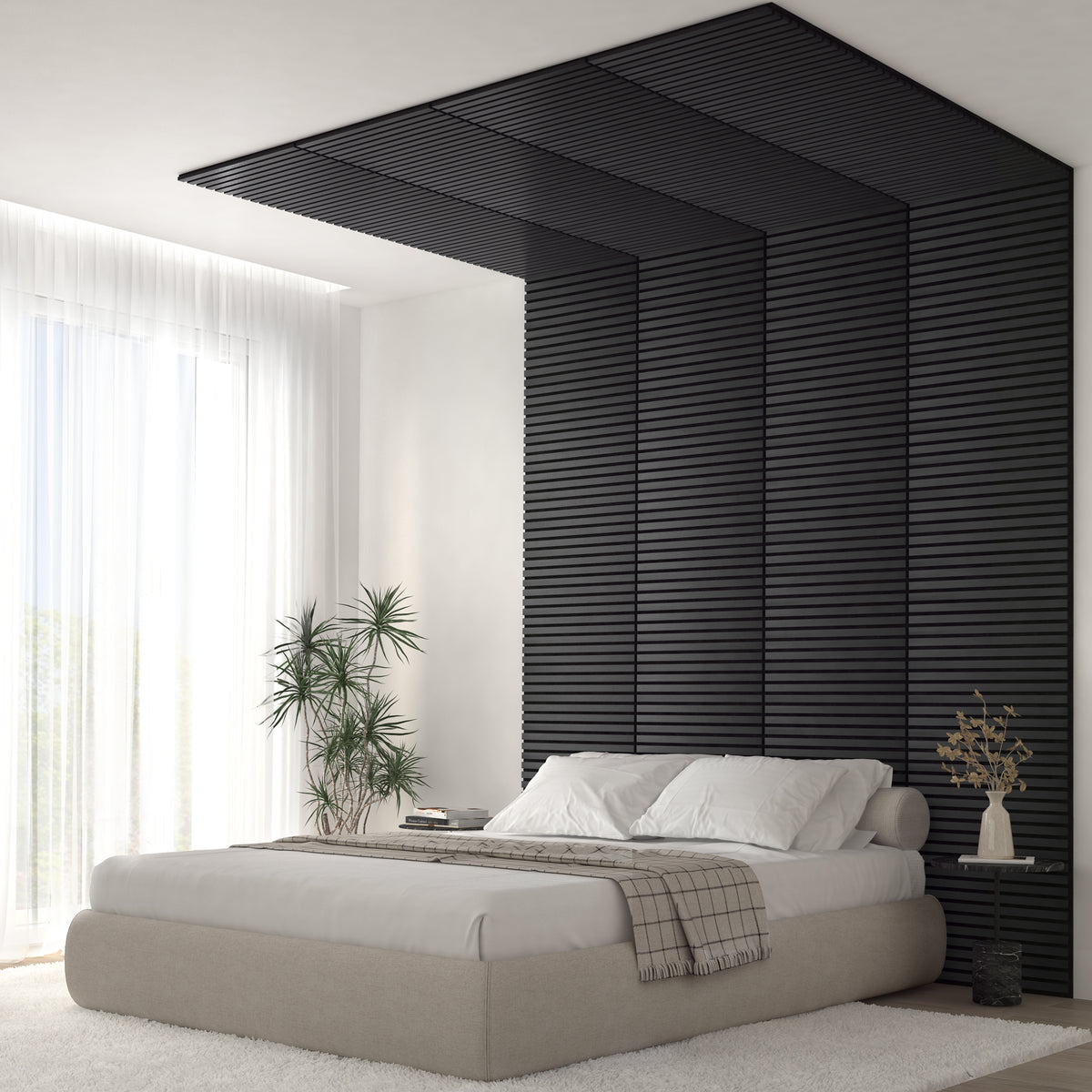 A modern bedroom with a low beige bed, white bedding, and a textured black accent wall that extends onto the ceiling. A potted plant and a vase with branches sit nearby; sheer curtains allow natural light to fill the room.
