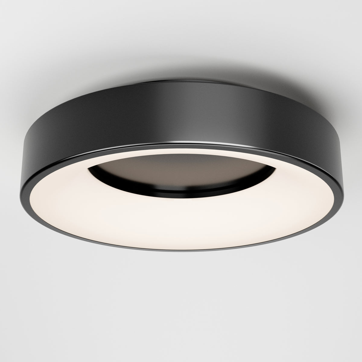A modern, round black ceiling light fixture with a wide, flat design and a glowing white diffuser, mounted on a plain white ceiling.