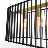 Close-up of a modern light fixture featuring exposed Edison bulbs and a rectangular black metal cage with vertical bars, accented by gold-toned hardware.