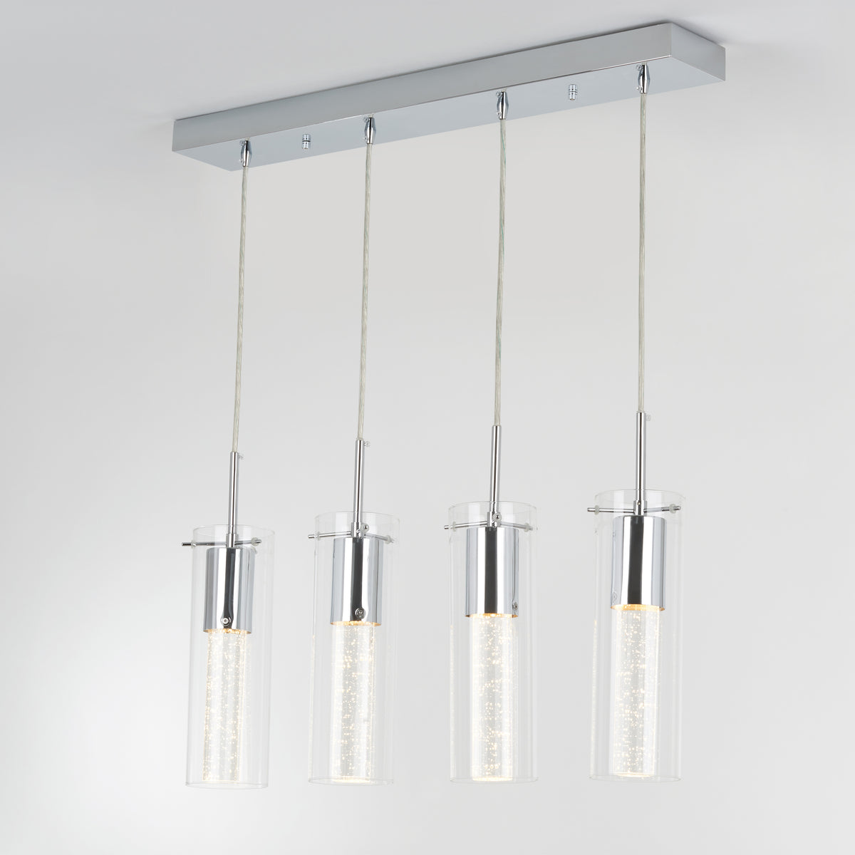 The Artika Bubble Flow 4-light pendant features four cylindrical glass lights with illuminated inner tubes, suspended from a rectangular chrome base against a plain white ceiling.