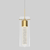 A modern pendant light with a cylindrical glass shade, brass accents, and an inner tube that appears to contain small sparkling bubbles, hanging from a thin cord against a plain gray background.