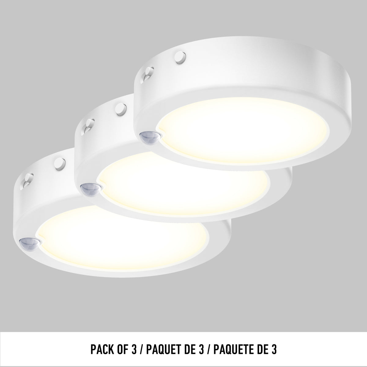 Three round, white LED puck lights are shown illuminated, arranged in a staggered row against a grey background. Text below reads: Pack of 3 / Paquet de 3 / Paquete de 3.