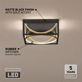 A modern ceiling LED light with a matte black finish and gold accent, featuring a rubber diffuser. Text highlights: no bulbs required, 5-year warranty, and integrated LED. Light is on against a beige wall.