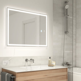 Modern bathroom with an Artika Aurea 24″x31″ Anti-Fog LED mirror, sink, soap dispensers, and glass shower with handheld head.