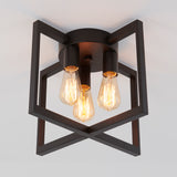 A modern ceiling light fixture with three exposed vintage-style filament bulbs, mounted within a black geometric metal frame against a white ceiling.