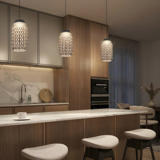 Modern kitchen with wooden cabinets, marble island with three cushioned stools, built-in ovens, and Artika's Benson Mini LED pendant lights (5 CCT) above the island. Adjustable color temperature creates a warm, inviting atmosphere.