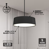 A modern black pendant light with an adjustable height hangs from the ceiling. Text highlights its steel construction with black finish, integrated LED, energy efficiency, and a 5-year warranty. Sheer curtains are in the background.
