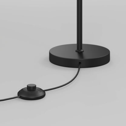 A close-up of the Artika Leni dimmable LED modern floor lamp’s black round base and cord with a round foot switch, shown against a plain light background.