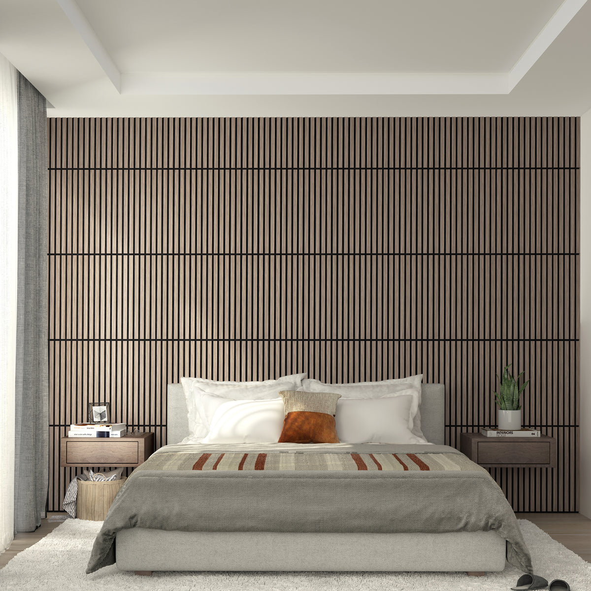 Modern bedroom with a padded gray bed, white and brown pillows, striped blanket, wood slat accent wall, matching bedside tables, potted plants, and soft natural light from a window with light curtains.