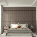 Modern bedroom with a padded gray bed, white and brown pillows, striped blanket, wood slat accent wall, matching bedside tables, potted plants, and soft natural light from a window with light curtains.