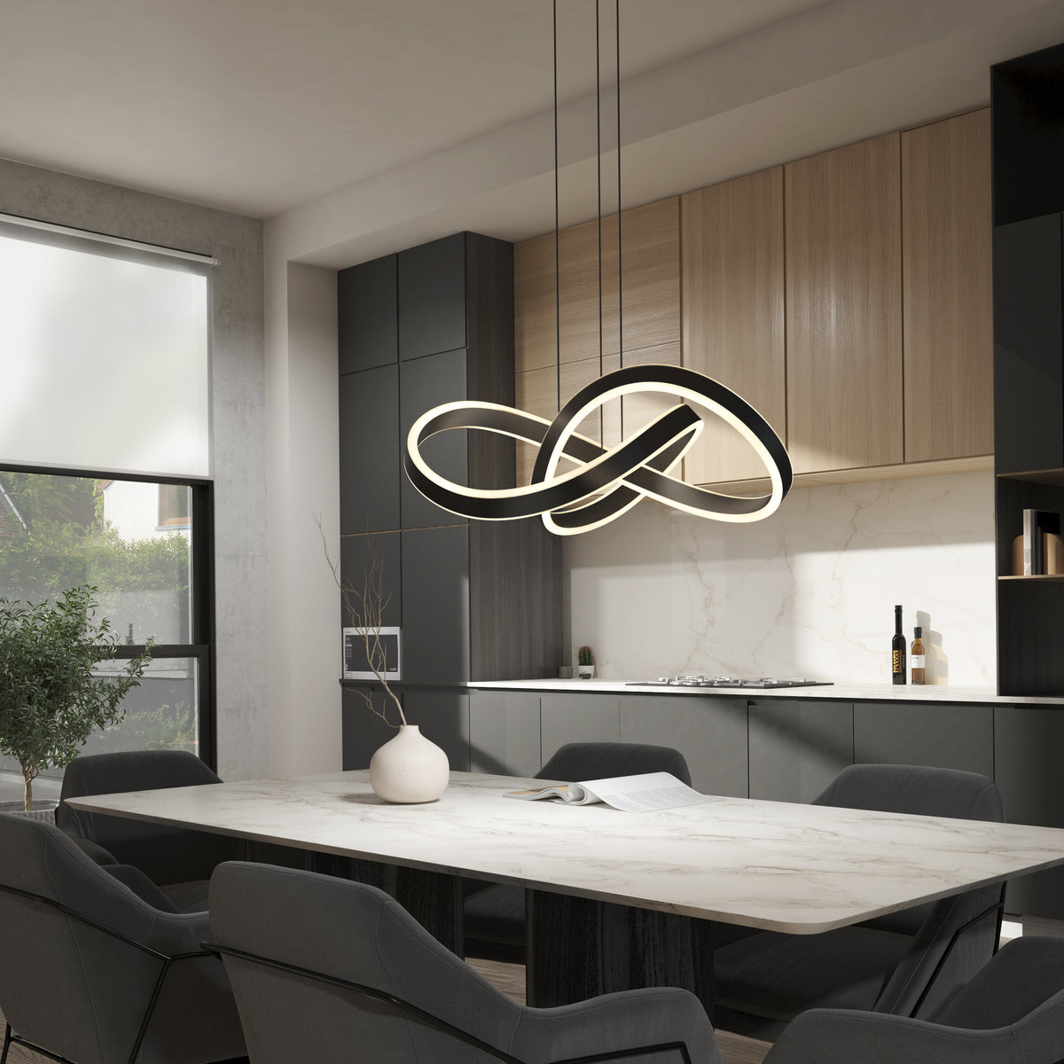 A modern dining room features a marble table, dark gray chairs, minimalist decor, and Artika’s Bolero LED pendant light 5 CCT with an abstract infinity shape suspended above. In the background, the kitchen has wood and black cabinetry.