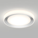 A modern, circular ceiling light fixture with a white rim and a glowing central disk, mounted on a plain light gray ceiling. The light emits a soft, even illumination.