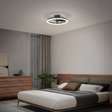 A modern bedroom with a wooden bed, white and gray bedding, a wooden dresser, a potted plant, and a ceiling fan with a circular light fixture. The walls are light-colored, and natural light enters through sheer curtains.