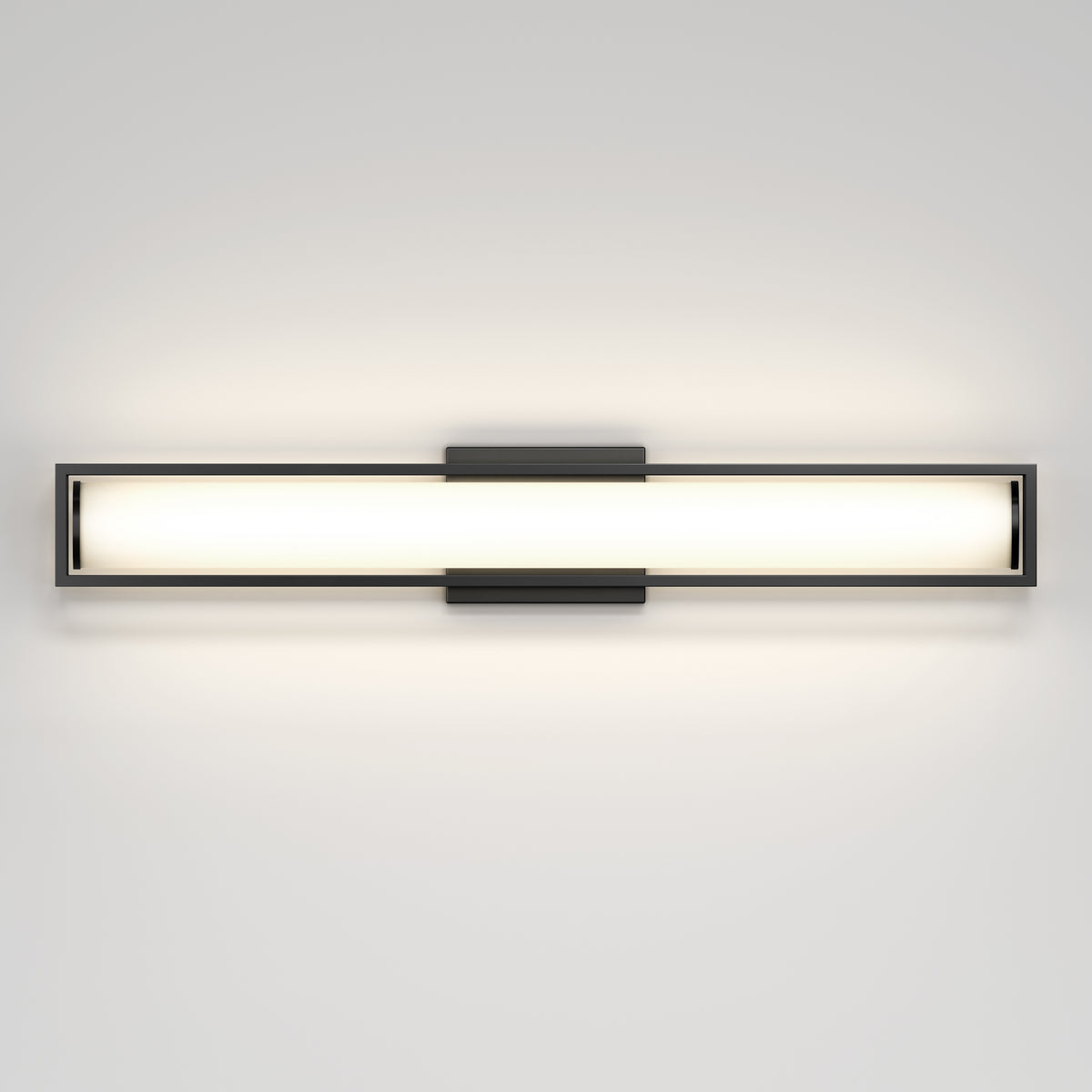 A modern, rectangular wall-mounted light fixture with a frosted glass center and metal frame, emitting a soft, even glow against a plain white wall.