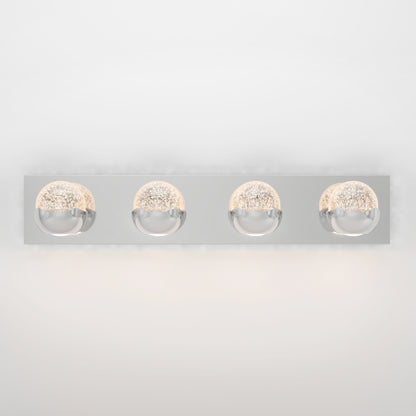 The Artika Oracle LED bathroom vanity light features a rectangular chrome base with four evenly spaced round bulb covers, emitting soft, warm light against a white background.