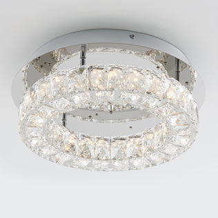 The Artika Celebrity LED flush mount light features two concentric circular rings with crystal accents on a metallic base, providing bright white illumination in a modern ceiling fixture.