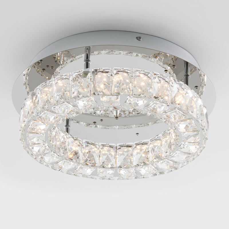 The Artika Celebrity LED flush mount light features two concentric circular rings with crystal accents on a metallic base, providing bright white illumination in a modern ceiling fixture.
