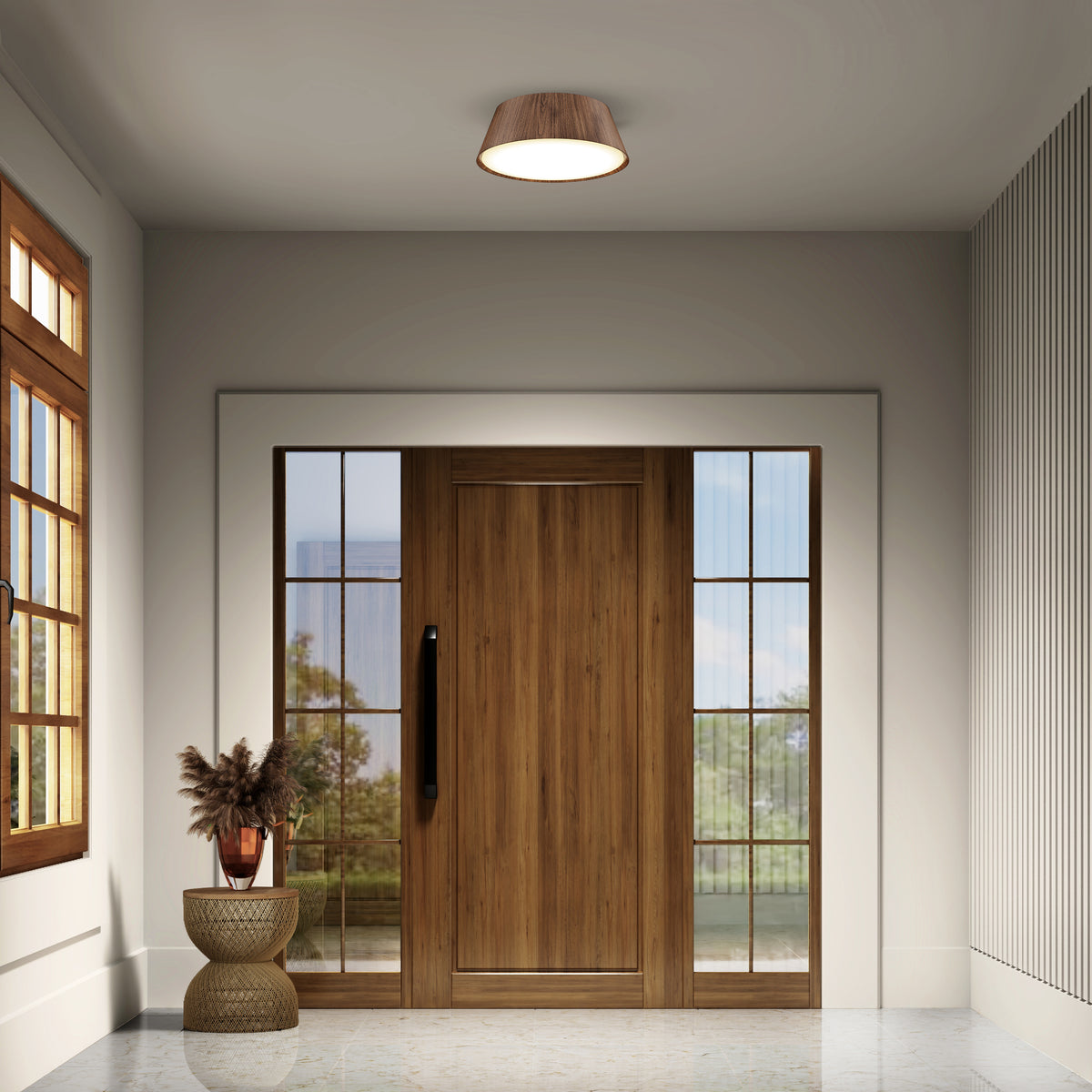 A modern entryway with a large wooden front door flanked by glass panels, a round light fixture on the ceiling, a window to the left, and a small table with a vase of dried plants and a bowl.