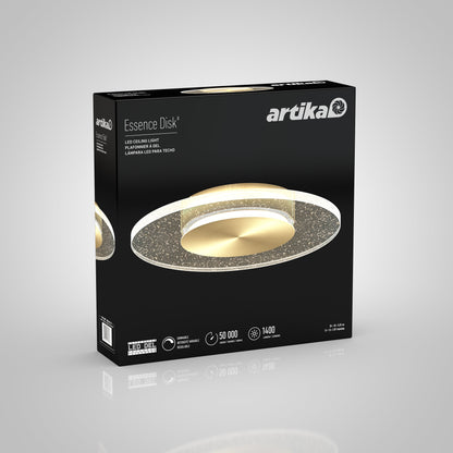 A black Artika-CAN-dev box showcases the Essence Disk LED flush mount, depicting the round fixture’s gold center and haloed glass diffuser. Lifespan and lumens are listed at the bottom of the packaging.