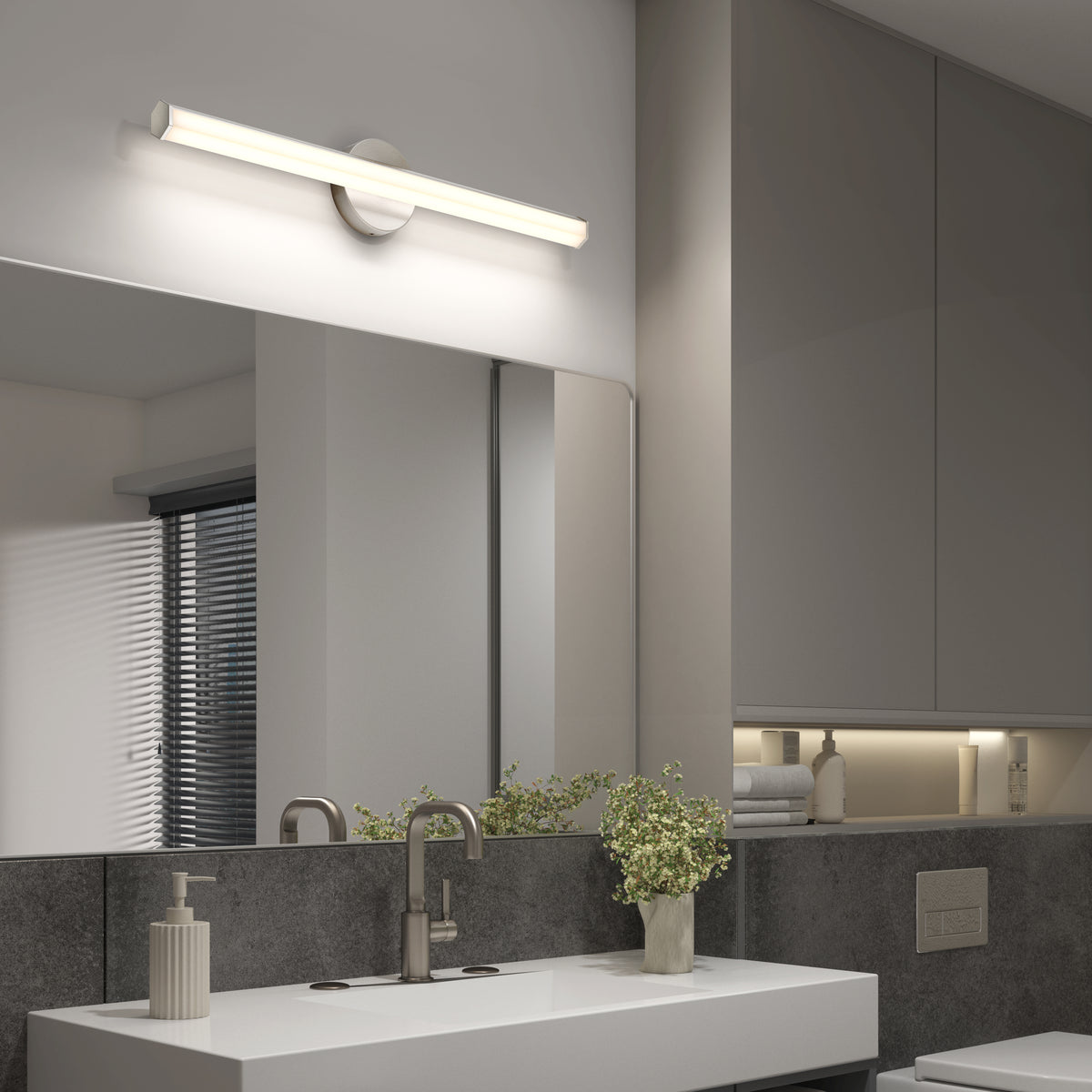 Modern bathroom with a wide mirror, sleek vanity, Artika Ewen LED light, faucet, soap dispenser, and plant by the sink.