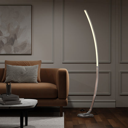 A modern living room with a brown sofa, striped pillow, round marble coffee table, and the Artika Arc LED Floor Lamp casting light over paneled gray walls and a dark wood floor.