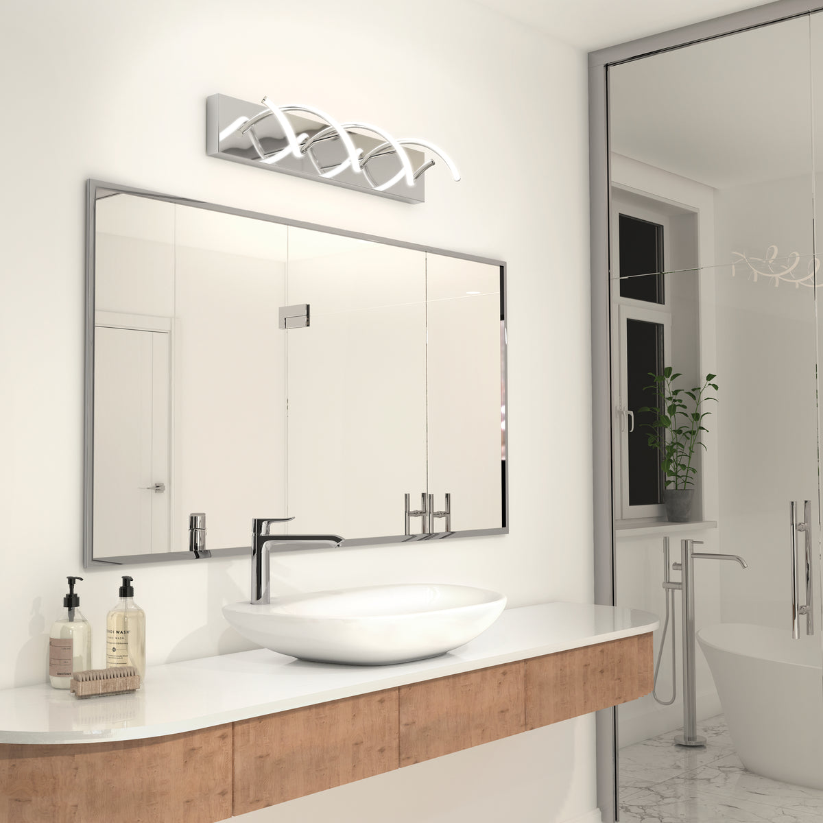 A modern bathroom features a large mirror, an oval sink on a wood vanity, soap dispensers, a decorative light fixture above the mirror, a glass shower, and a window with a plant on the sill.