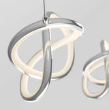 A modern, sculptural LED pendant light with smooth, intertwined silver loops and a soft inner glow, hanging from a thin cable against a neutral gray background. Another similar light is blurred in the background.