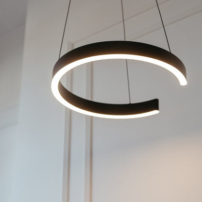 The Artika Vance modern LED pendant light 3 CCT, featuring a circular design with a gap and suspended by two wires, casts a soft white glow against a minimal white wall backdrop.