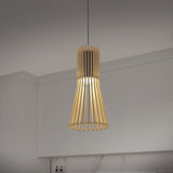 A modern pendant light with a wooden slatted design hangs from the ceiling in a minimalist kitchen with white cabinets and a marble backsplash.