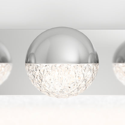 The Artika Carat LED bathroom vanity light features a modern half-sphere design with a smooth metallic top and a faceted, crystal-like lower half that beautifully refracts light.