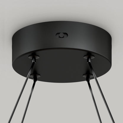 Close-up view of a black, round ceiling mount with four cables extending downward, attached to the bottom surface, likely part of a modern hanging light fixture.