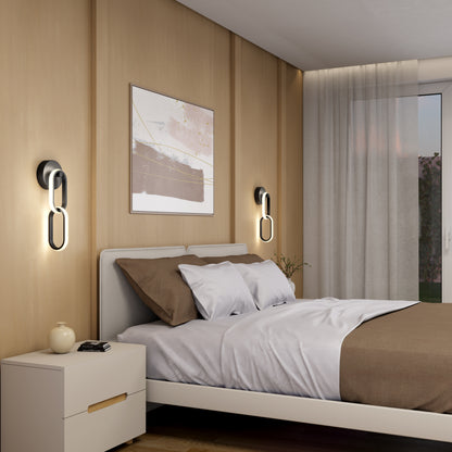 Modern bedroom with a light wood accent wall, double bed with brown and white bedding, Artika Catena modern LED wall sconces, nightstand with vase and cup, sheer curtains, and framed abstract artwork above the bed.