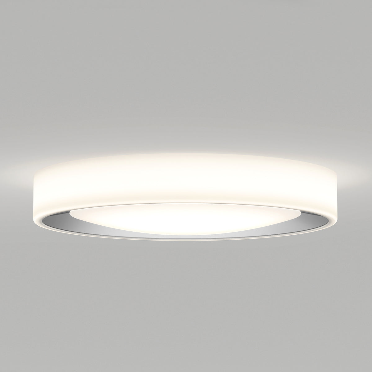 A modern, round, white ceiling light fixture with a sleek, minimal design, emitting a soft, diffused glow against a plain light gray ceiling.