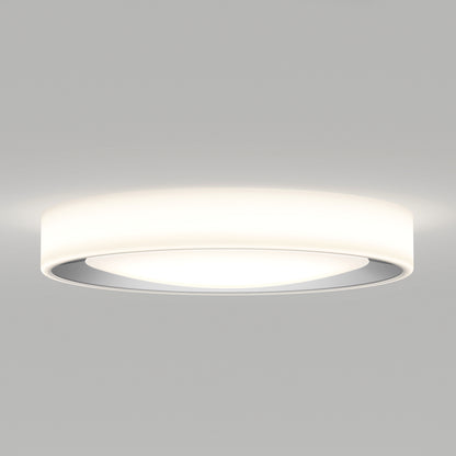 The Artika Cooper LED flush mount light features a sleek, minimalistic circular design with smooth edges and a slightly recessed center. It emits a soft, even white glow and comes with a remote for easy control.