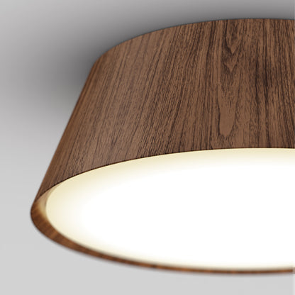 Close-up of the Artika Dunham 15 in. LED flush mount light featuring a wooden-textured lampshade and glowing white light, set against a neutral gray background. Offers 5 CCT options for customizable ambiance.