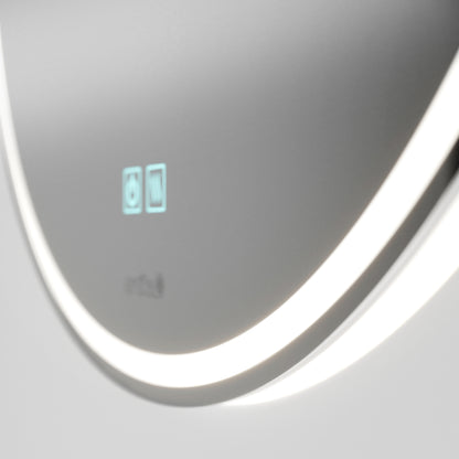A close-up of the Artika Emeraude anti fog LED wall mirror shows its sleek design, glowing white LED light ring, and two blue illuminated touch icons on a smooth metallic surface.