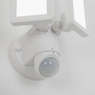 A close-up of the Artika Sentinel outdoor Flat Panel Security light, featuring two rectangular LED panels and a round motion sensor, mounted on a white wall.