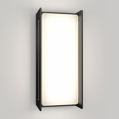 The Artika Ryker smart RGB indoor-outdoor wall light features a rectangular frosted glass panel framed by two vertical black metal sides, emitting customizable light against a light gray wall.