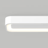 A minimalist white rectangular LED light fixture with rounded corners mounted on a plain gray wall, emitting a soft, even glow from its inner edge.