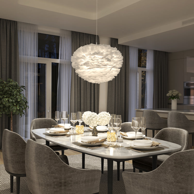 A modern dining room features a marble table for six, gray upholstered chairs, elegant place settings, large windows with sheer curtains, and a Plume LED pendant light by Artika above white flowers at the center of the table.