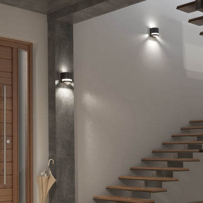 Modern staircase with floating wooden steps, an Artika Valor Round LED wall light, and umbrella stand by a sleek wooden door.