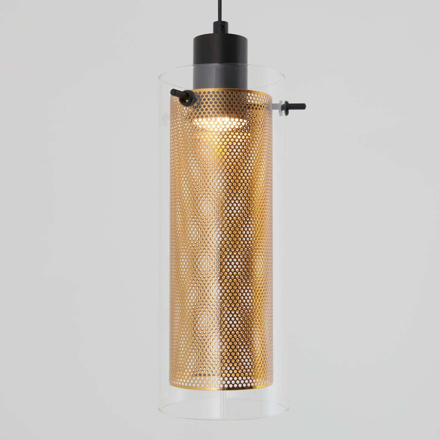 The Artika Oxion 1-light LED pendant features a cylindrical gold perforated metal shade inside a clear glass cylinder, hanging from a black cord against a gray background.