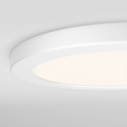 A close-up of the Artika Europa Disk 9 in. LED modern flush mount light (3 CCT) softly glowing against a white ceiling.