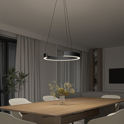 A modern dining room features a wooden table, beige chairs, and the Artika Vance modern LED pendant light 3 CCT in black hanging above. A glass vase with dried flowers sits on the table, with neutral curtains and built-in shelves in the background.