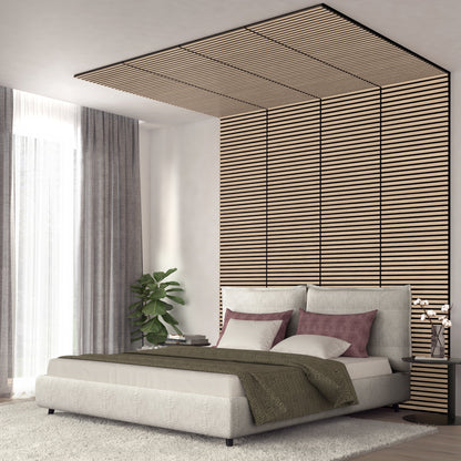 Modern bedroom with a low beige bed, green blanket, and mauve pillows. Behind the bed, Artika-CAN-devs Sonolok 15.5 ft sound-absorbing wall panel kit features horizontal wooden slats. A potted plant and gray-curtained window are on the left.