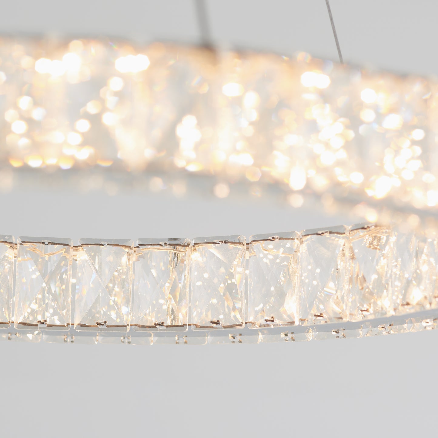 Close-up of the Artika Celebrity LED pendant light, featuring sparkling crystal accents that emit a bright, warm glow. The image highlights the crystals in focus, with a softly blurred, glowing background.