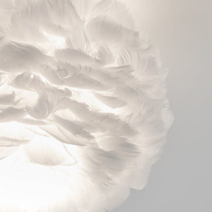 The Artika Plume LED flush mount light features soft, white feather-like elements arranged in a circular design, illuminated from below for a light, airy ambiance against a pale background.
