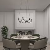A modern dining room with a round table set for five, surrounded by upholstered chairs. A black, sculptural chandelier hangs above. There’s a fireplace in the background and a potted plant to the left. The decor is minimalist and elegant.
