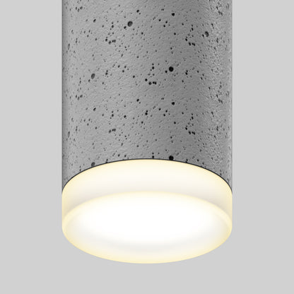 A close-up of the Artika Barden 1-light LED pendant 5 CCT, featuring a cylindrical, textured concrete design and a warm glow from beneath, set against a plain gray background.