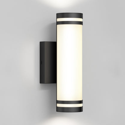 A modern wall-mounted cylindrical light fixture with a black frame and frosted white diffuser, emitting light both upward and downward against a plain gray wall.
